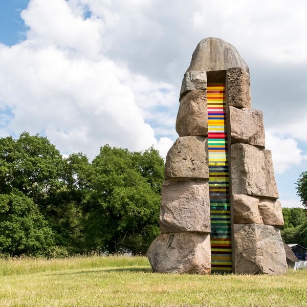 Bunte Steinskulptur auf einer grünen Wiese. 