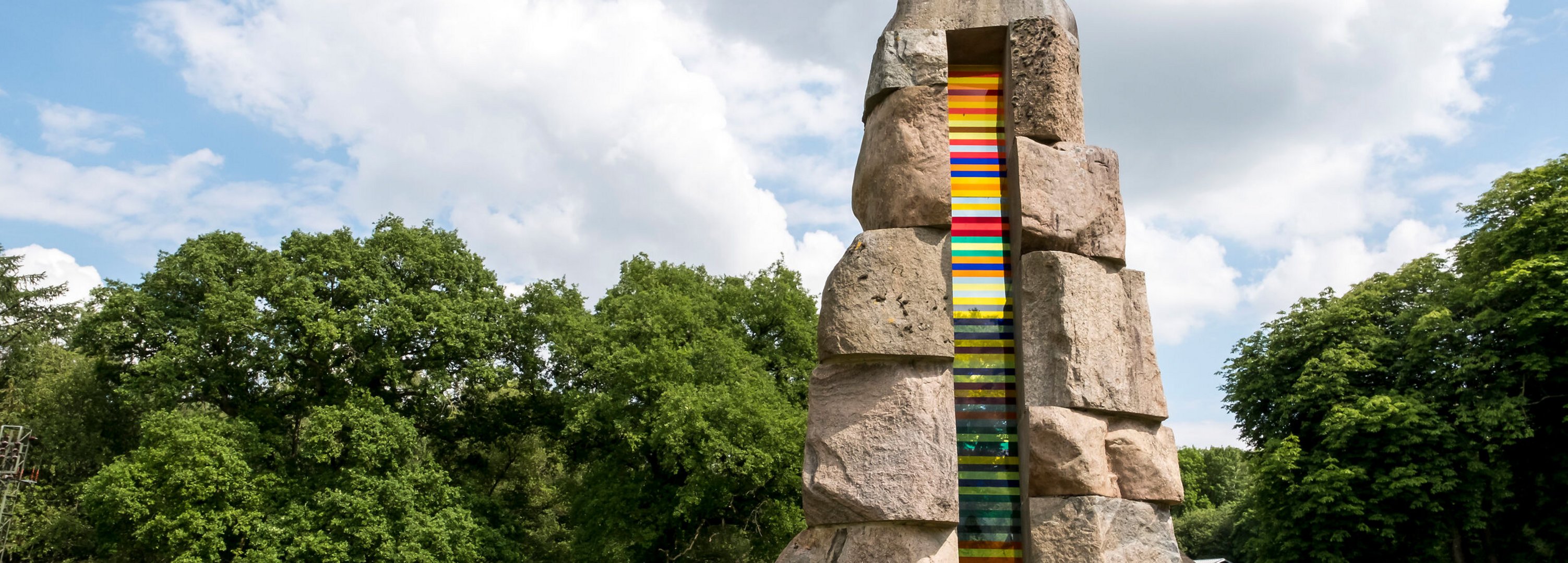 Bunte Steinskulptur auf einer grünen Wiese. 