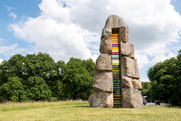 Bunte Steinskulptur auf einer grünen Wiese. 