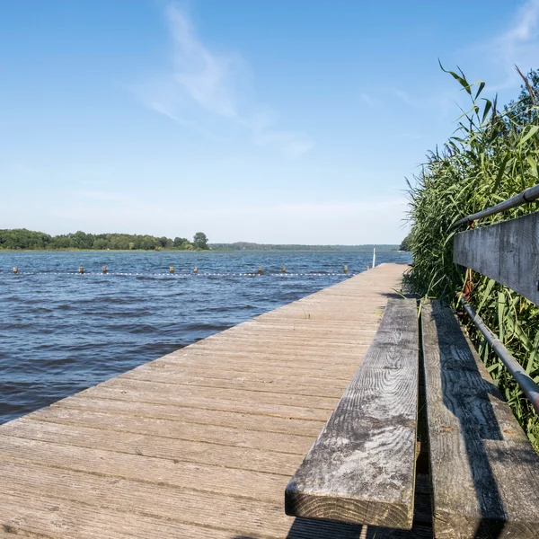 Badestelle Westensee_1 (© MHT.SH & Peter Lühr) Ein Holzsteg mit einer Holzbank führt in das blaue Seewasser hinein. Der Himmel ist blau und es ist Sommer.