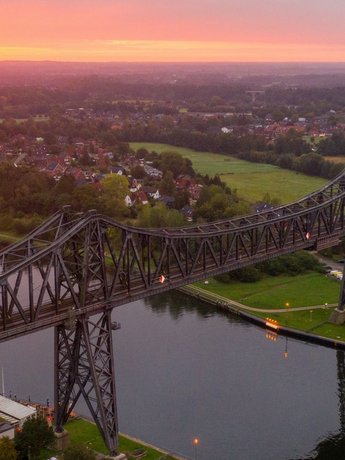 (© sh-tourismus.de / MOCANOX) Luftaufnahme der Rendsburger Hochbrücke und des Nord-Ostsee-Kanals bei Sonnenuntergang