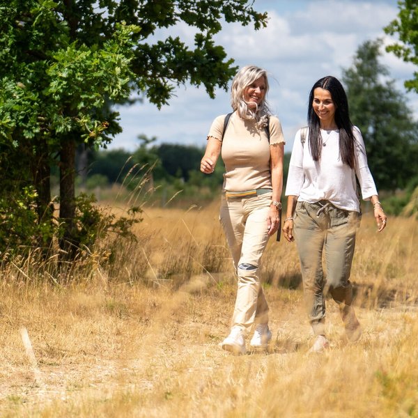 Zwei Frau wandern durch eine idyllische Naturlandschaft in einem Naturpark.