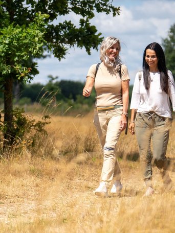 Zwei Frau wandern durch eine idyllische Naturlandschaft in einem Naturpark.