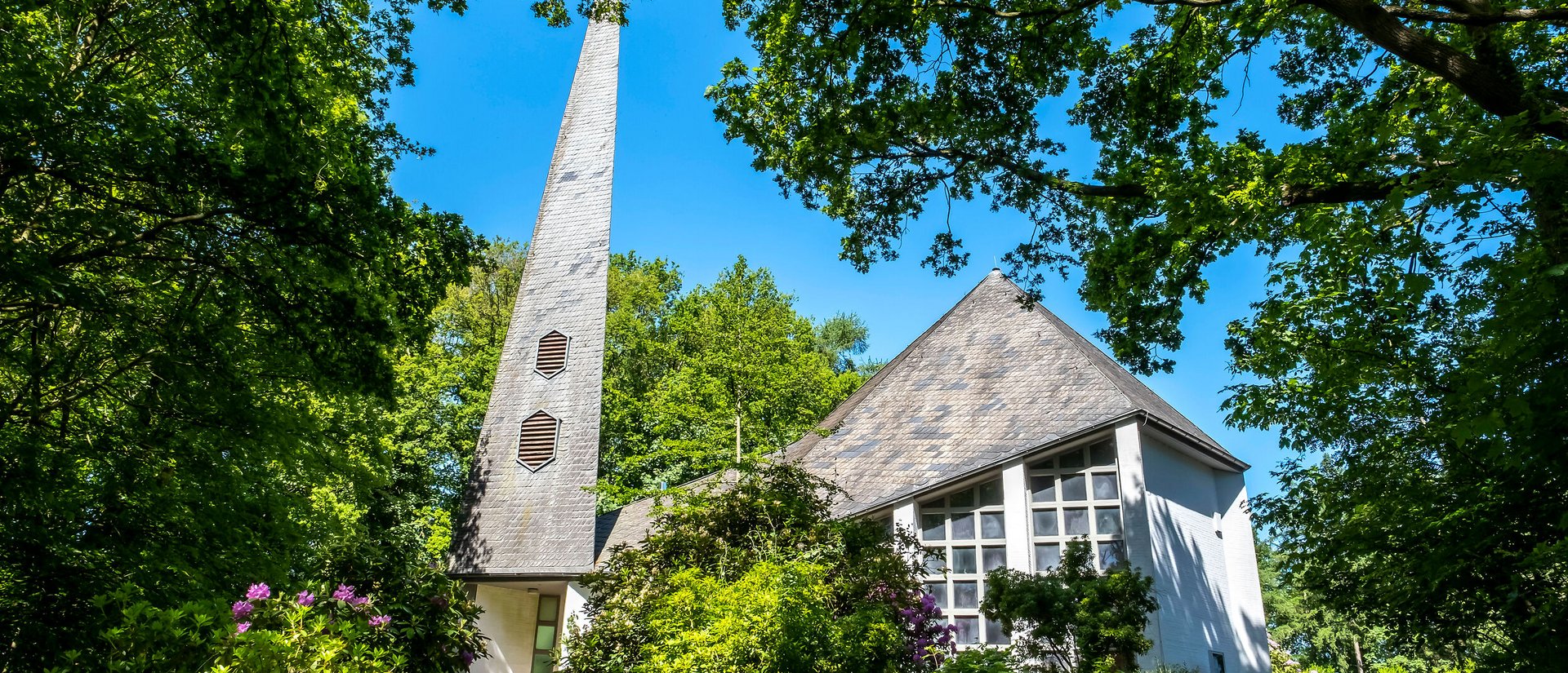 Weiße St. Johanneskirche unter grünen Bäumen in Gokels im Amt Mittelholstein
