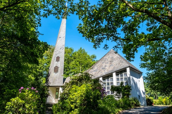 Weiße St. Johanneskirche unter grünen Bäumen in Gokels im Amt Mittelholstein