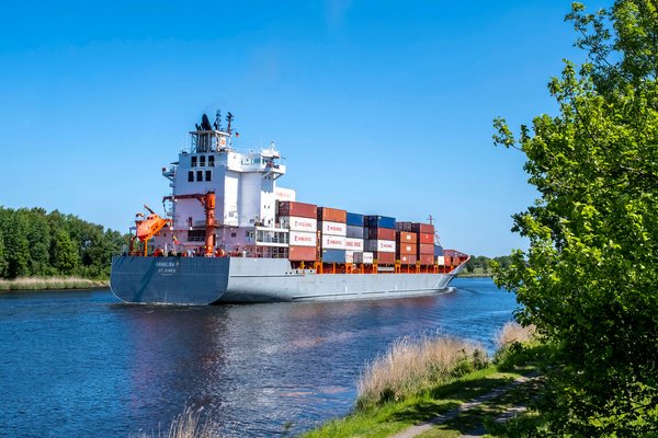 Ein Kontainerschiff fährt auf der Nord-Ostsee-Kanal an der Gemeinde Tackesdorf Amt Mittelholstein vorbei