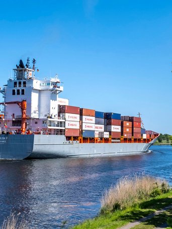 Ein Kontainerschiff fährt auf der Nord-Ostsee-Kanal an der Gemeinde Tackesdorf Amt Mittelholstein vorbei