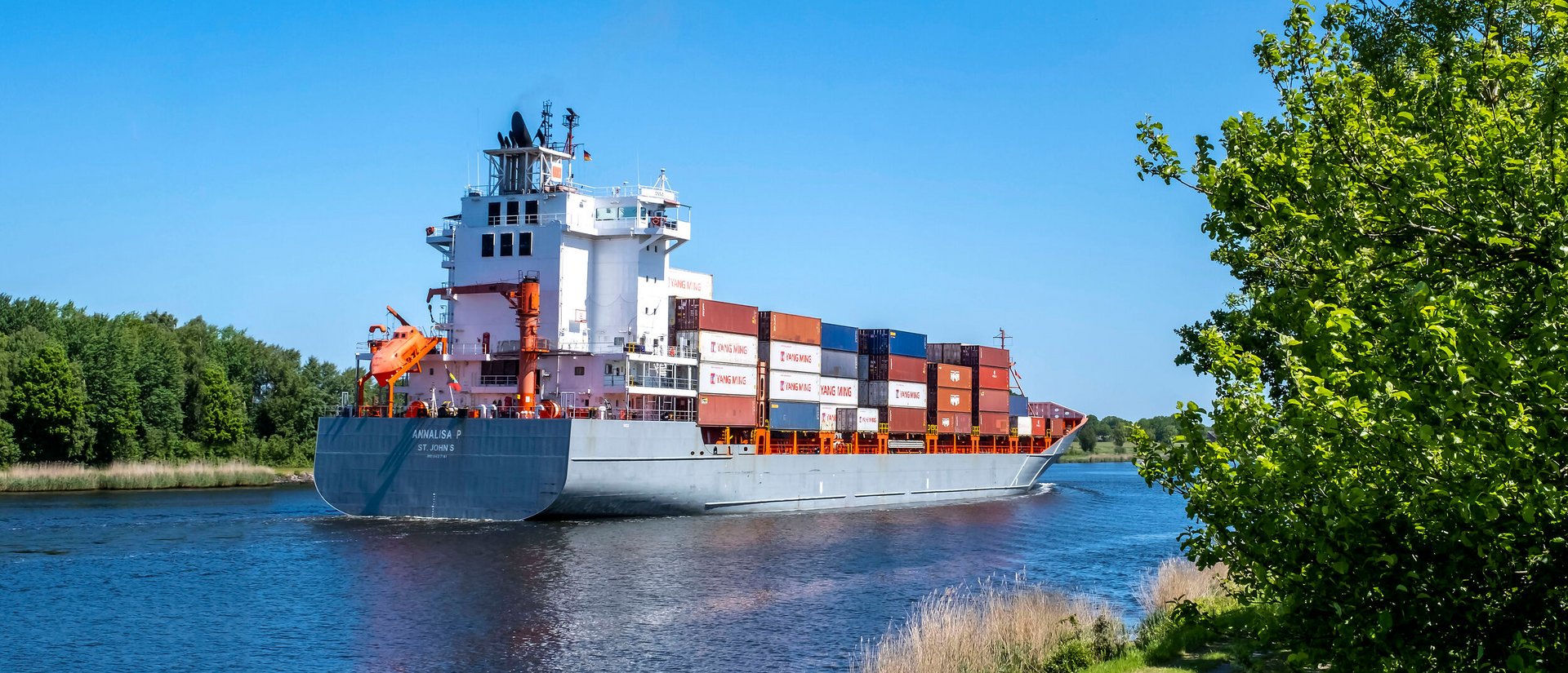 Ein Kontainerschiff fährt auf der Nord-Ostsee-Kanal an der Gemeinde Tackesdorf Amt Mittelholstein vorbei