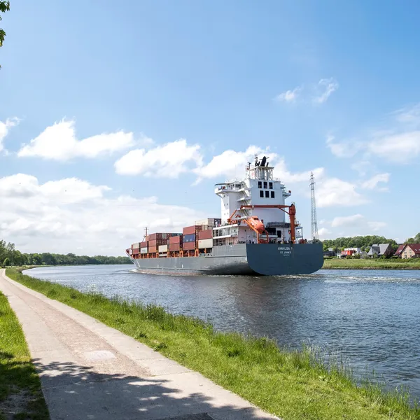 Ein großes Containerschiff fährt auf dem NOK entlang. Der Himmel ist blau.
