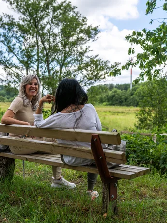 Naturpark Wanderweg (sh-tourismus.de/MOCANOX) Zwei Frauen sitzen auf einer Bank im Naturpark Aukrug.