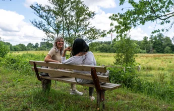 Naturpark Wanderweg (sh-tourismus.de/MOCANOX) Zwei Frauen sitzen auf einer Bank im Naturpark Aukrug.