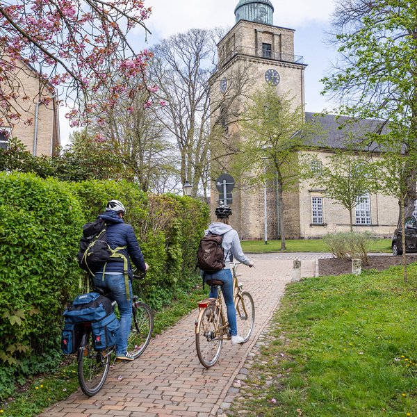Zwei Radfahrer fahren im Frühling auf eine Kirche zu.