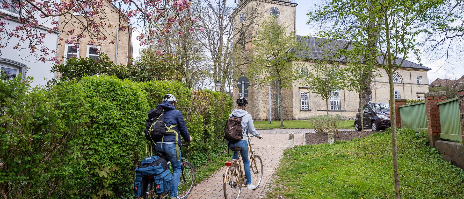 Zwei Radfahrer fahren im Frühling auf eine Kirche zu.