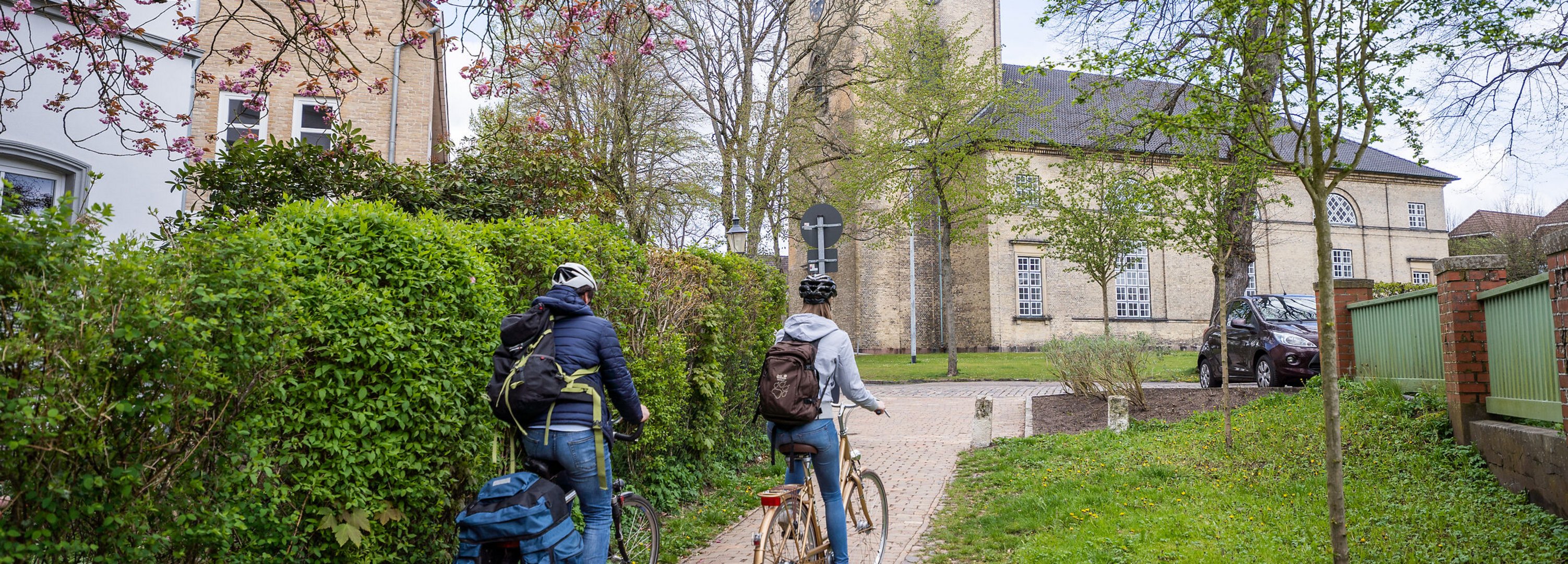 Zwei Radfahrer fahren im Frühling auf eine Kirche zu.