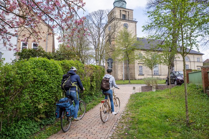 Zwei Radfahrer fahren im Frühling auf eine Kirche zu.