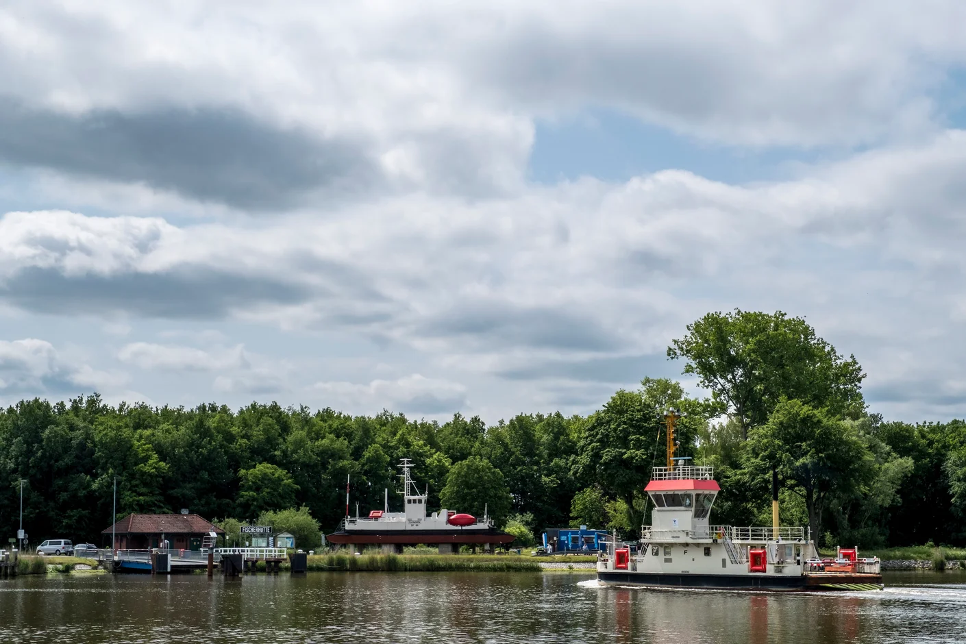 Steenfeld und Fischerhütte am NOK_7 Kanal Fähre Fischerhütte auf dem Wasser. Im Hintergrund liegt die historische Kettenfähre am Ufer.
