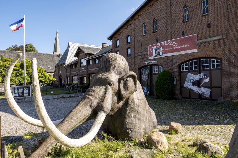 Eingang des Museums 'Tor zur Urzeit' mit einer Mammutstatue im Vordergrund.