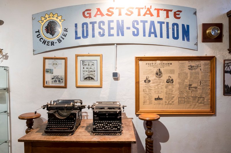 Historische Schreibmaschinen und alte Schilder in einem Museum.