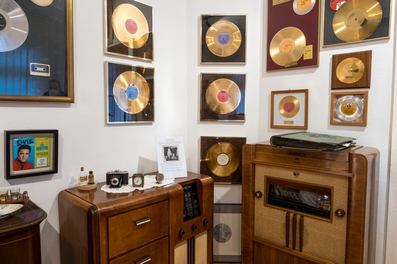 Innenansicht eines Museums mit goldenen Schallplatten an der Wand und einem alten Radio.