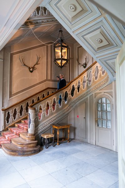 Innenansicht eines historischen Treppenhauses mit Holzgeländer und Hirschgeweihen an der Wand.
