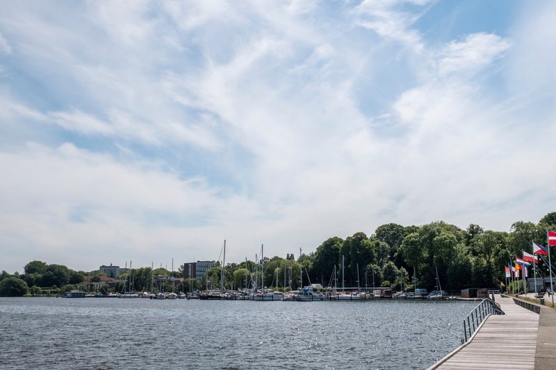 Ansicht des Obereiderhafens in Rendsburg mit Segelbooten und einer Promenade mit Flaggen.