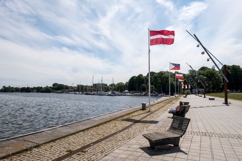 Promenade am Obereiderhafen in Rendsburg mit Flaggen und Bänken entlang des Wassers.