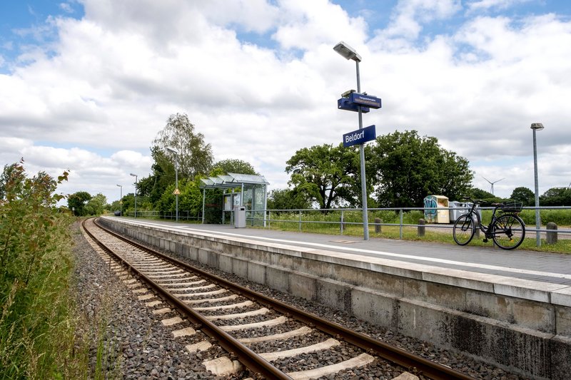 Bahnhof Beldorf mit Gleisen, Wartehäuschen und Fahrrad.