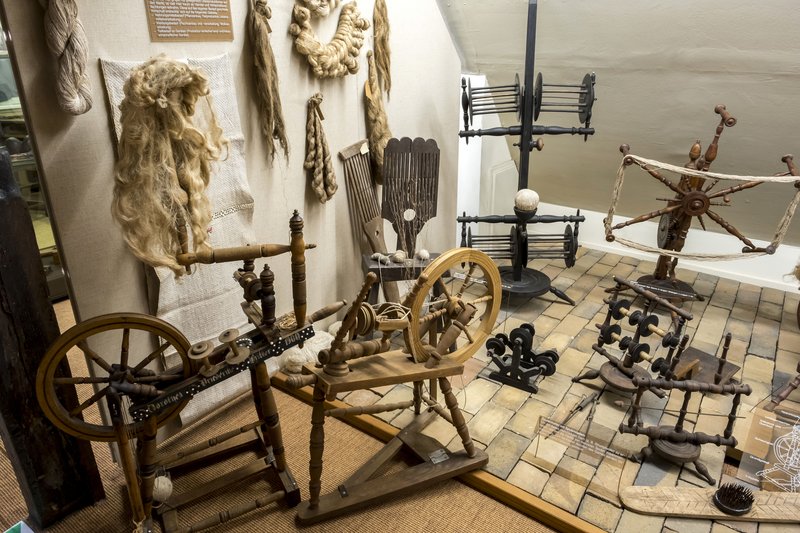 Historische Spinnräder und Textilwerkzeuge in einem Museum ausgestellt.