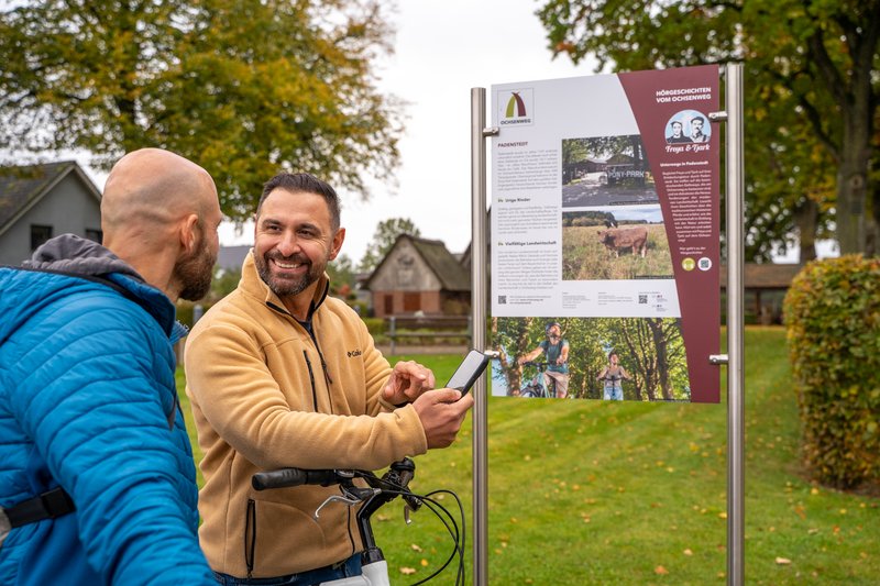 Zwei Männer stehen vor einer Informationstafel am Ochsenweg in Padenstedt.