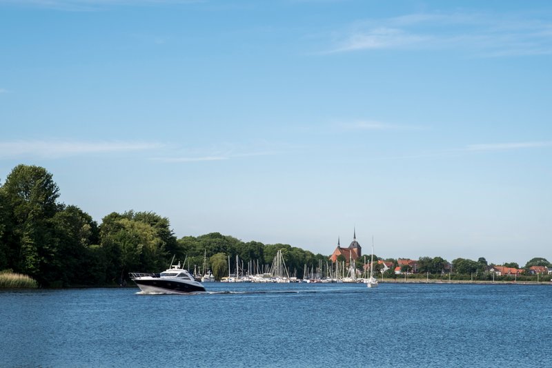 Ein Boot fährt durch den Obereiderhafen mit einer Kirche im Hintergrund.