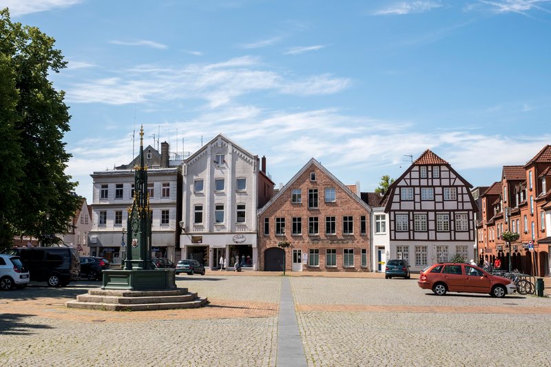 Historische Gebäude am Schlossplatz in Rendsburg mit einem Brunnen im Vordergrund.