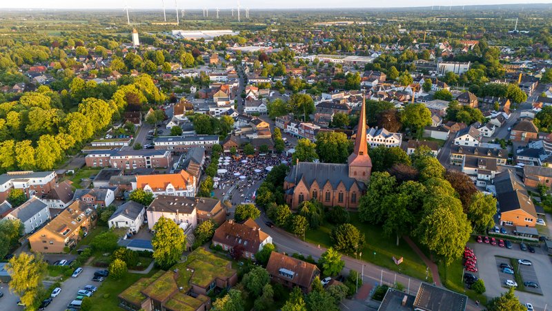 Luftaufnahme von Nortorf mit Kirche und umliegenden Gebäuden, umgeben von Bäumen und Grünflächen.