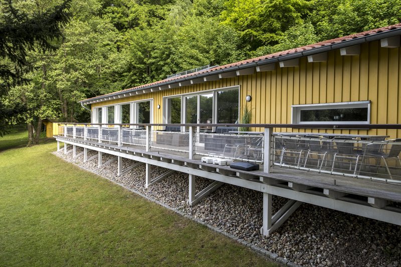 Gelbes Gebäude mit Terrasse im Grünen.