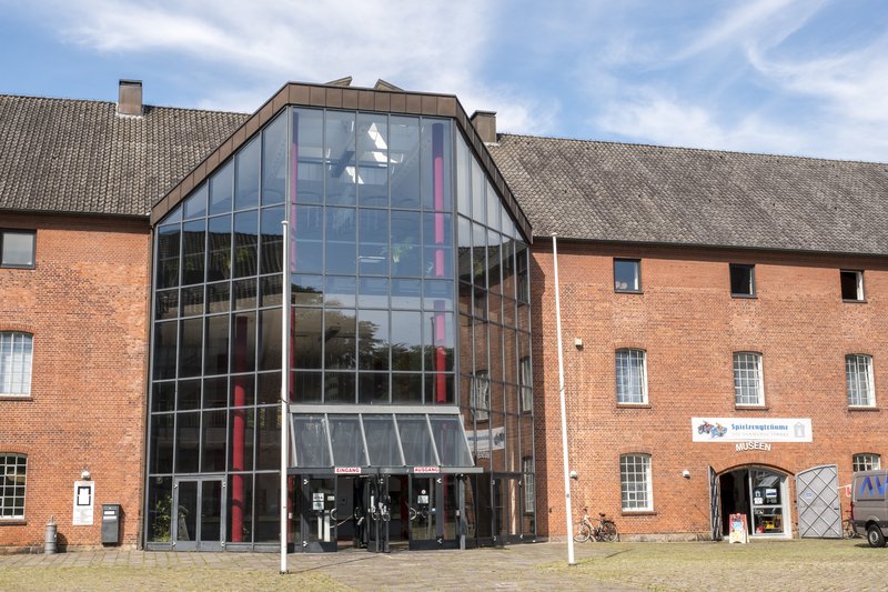 Eingang des Kulturzentrums Rendsburg mit Glasfassade und Backsteinmauern.