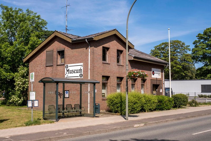 Backsteingebäude mit Schild 'Museum' und Bushaltestelle davor.