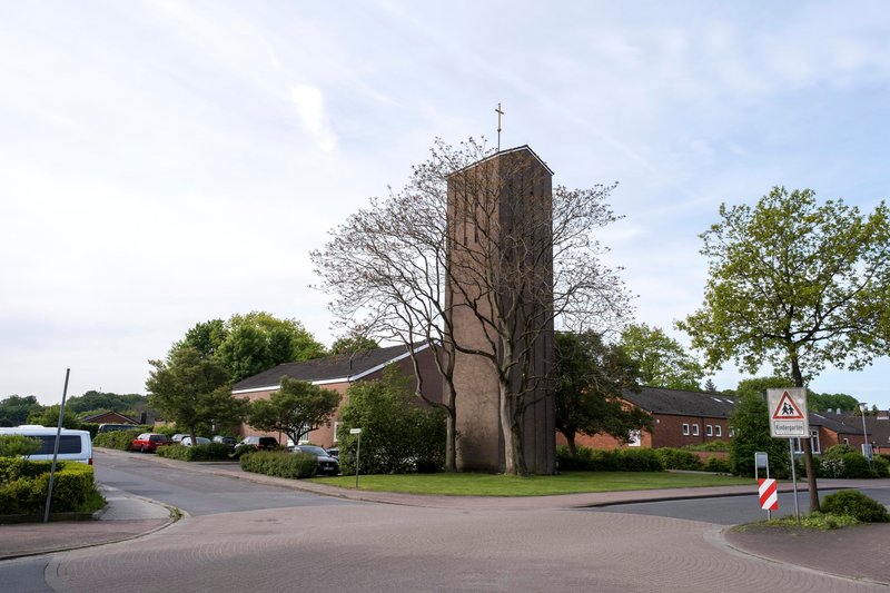 Außenansicht der Auferstehungskirche in Büdelsdorf mit Turm und umliegenden Bäumen.