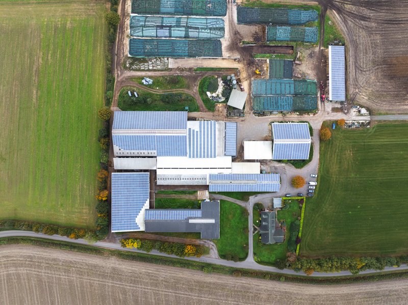 Luftaufnahme des landwirtschaftlichen Betriebs Hof Neuhörn mit Solarpaneelen auf den Dächern.