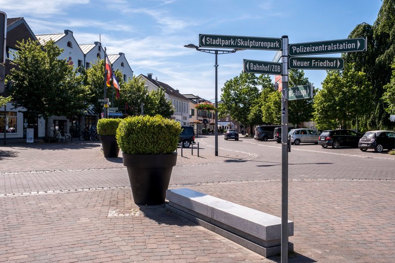 Marktplatz in Nortorf mit Wegweisern und großen Pflanzkübeln.